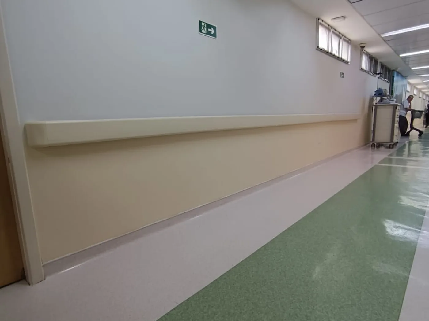 Corrimão bege acompanhando a parede de um corredor de circulação